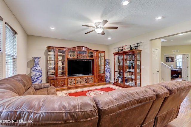 living area featuring plenty of natural light, visible vents, ceiling fan, and wood finished floors