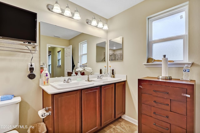 bathroom with toilet, plenty of natural light, and a sink