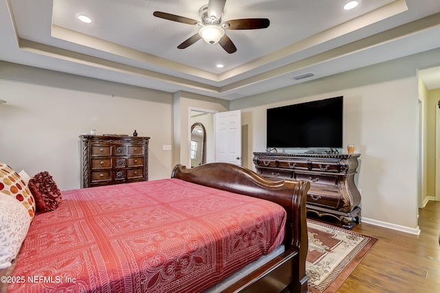 bedroom with visible vents, recessed lighting, a raised ceiling, and wood finished floors