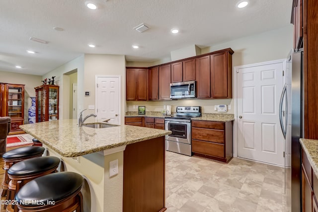 kitchen featuring a sink, light stone countertops, a kitchen bar, and stainless steel appliances