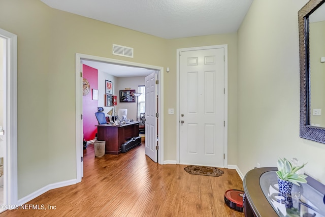 entryway featuring visible vents, baseboards, and wood finished floors