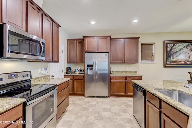 kitchen featuring light stone counters, stainless steel appliances, recessed lighting, and a sink