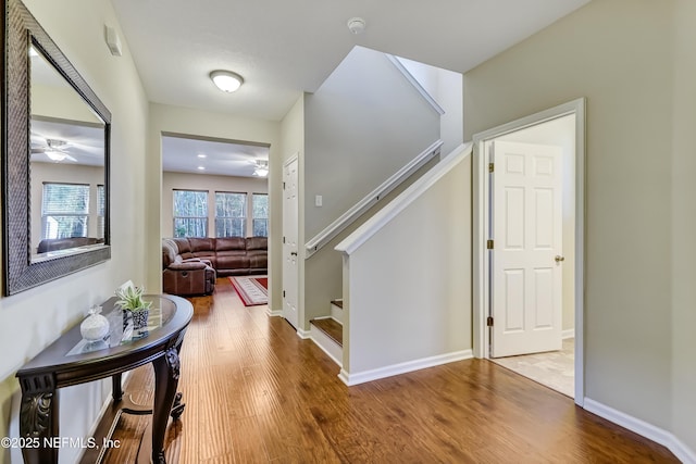 interior space with stairs, wood finished floors, a ceiling fan, and baseboards