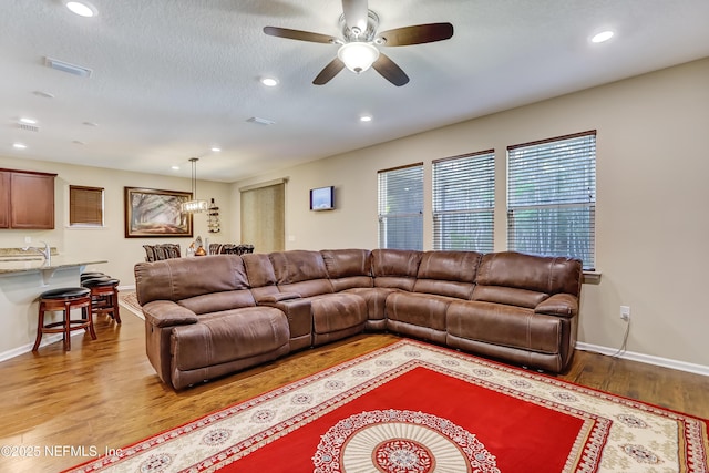 living room featuring visible vents, ceiling fan, light wood-type flooring, recessed lighting, and a textured ceiling