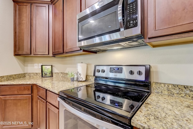 kitchen featuring light stone counters, brown cabinetry, and appliances with stainless steel finishes