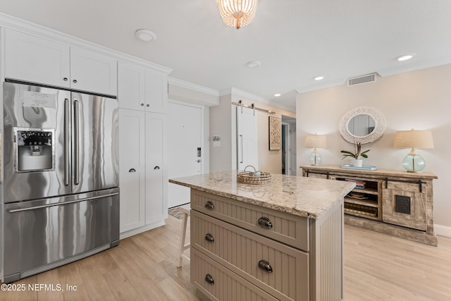 kitchen featuring light stone counters, visible vents, light wood finished floors, stainless steel fridge with ice dispenser, and crown molding