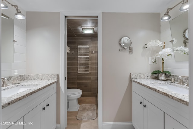 full bathroom with two vanities, a tile shower, and a sink