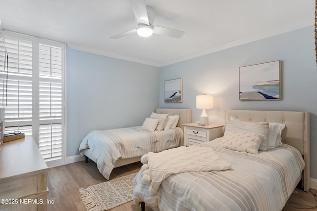 bedroom featuring a ceiling fan, wood finished floors, baseboards, and ornamental molding