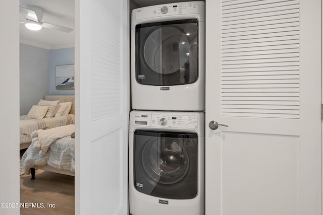 clothes washing area with wood finished floors, ornamental molding, laundry area, and stacked washing maching and dryer