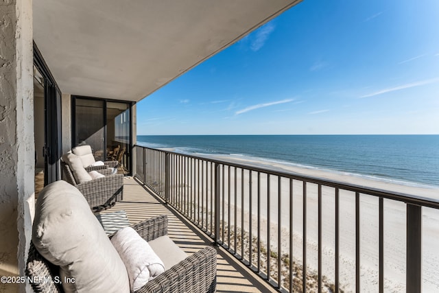 balcony featuring a water view and a beach view