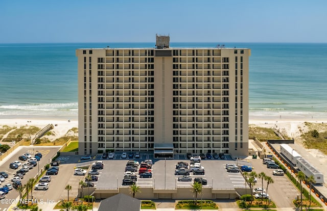 view of property featuring uncovered parking, a beach view, and a water view