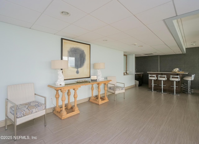 interior space with bar, baseboards, and a drop ceiling