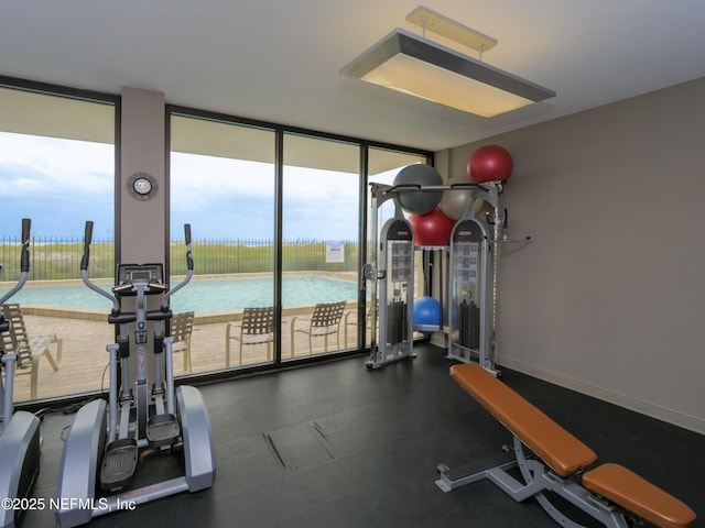 exercise room featuring floor to ceiling windows and baseboards