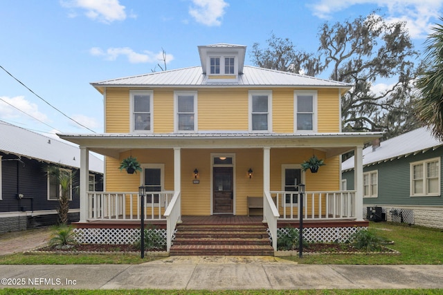 traditional style home with metal roof, a porch, and central AC