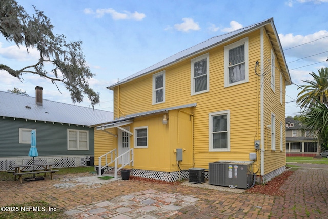 back of house with a patio area, central AC unit, entry steps, and metal roof