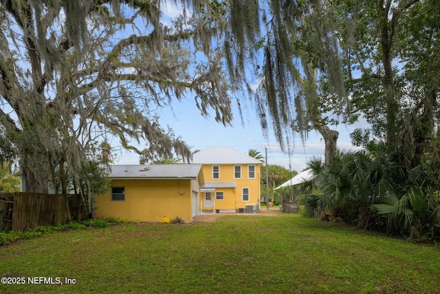 back of house with a yard, fence, and central AC