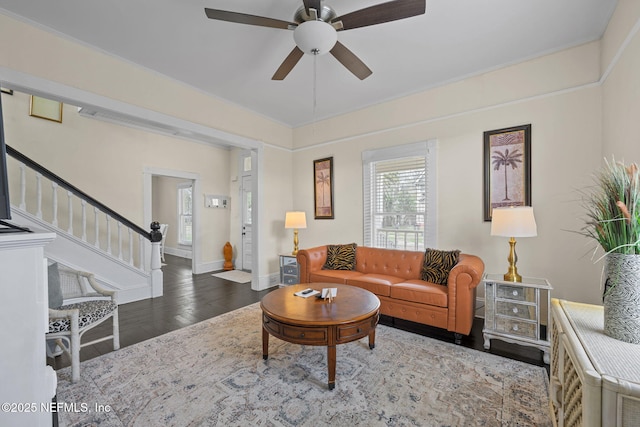 living room with ceiling fan, baseboards, wood finished floors, and stairs