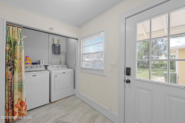 clothes washing area featuring laundry area, baseboards, a wealth of natural light, and washing machine and clothes dryer