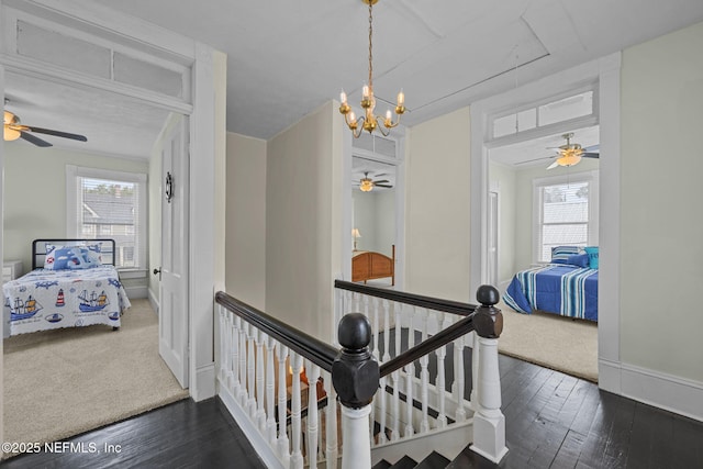 hallway featuring an upstairs landing, a healthy amount of sunlight, and wood finished floors