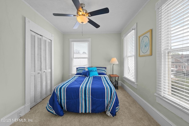 carpeted bedroom with a closet, multiple windows, crown molding, and baseboards