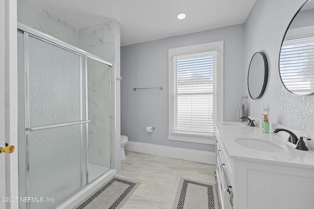 bathroom with a sink, baseboards, toilet, and a shower stall