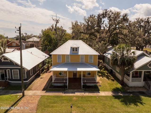 view of front of house featuring a front lawn, covered porch, driveway, and metal roof