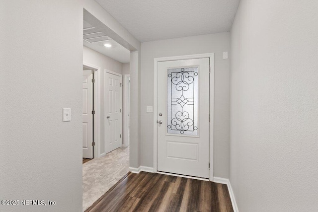 foyer with dark wood finished floors, baseboards, and a textured ceiling