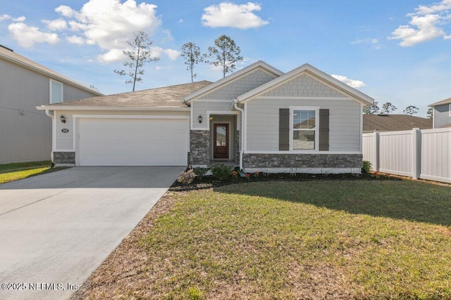 view of front of property with stone siding, fence, concrete driveway, a front yard, and a garage