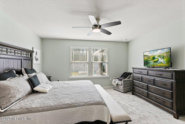 bedroom with light colored carpet, a textured ceiling, and a ceiling fan