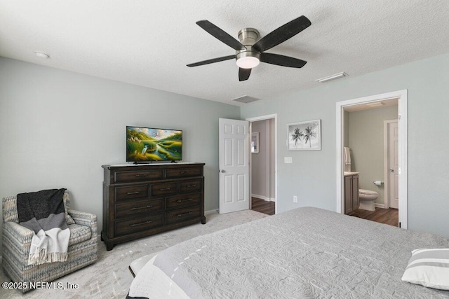 bedroom featuring visible vents, a textured ceiling, ensuite bathroom, and a ceiling fan