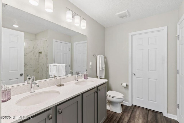 full bath with toilet, visible vents, a marble finish shower, and a sink