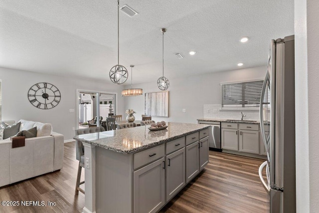 kitchen featuring open floor plan, appliances with stainless steel finishes, gray cabinetry, and dark wood-style flooring