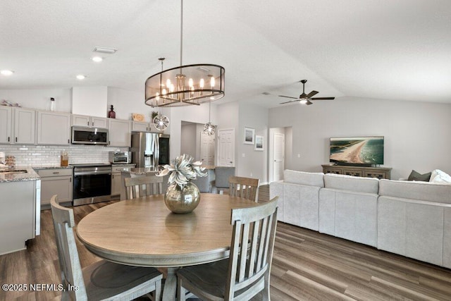 dining area with dark wood-style floors, lofted ceiling, a toaster, a textured ceiling, and ceiling fan with notable chandelier