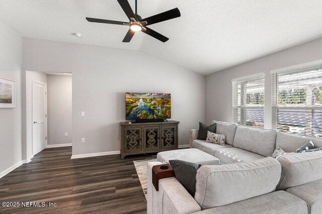 living area with a textured ceiling, dark wood-style floors, baseboards, ceiling fan, and vaulted ceiling