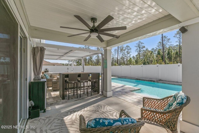 view of swimming pool featuring a ceiling fan, a fenced in pool, a fenced backyard, a patio area, and outdoor dry bar