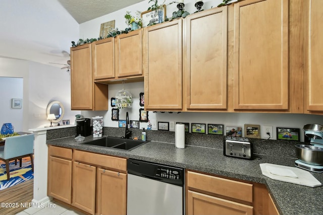 kitchen with dishwasher, dark countertops, a ceiling fan, and a sink