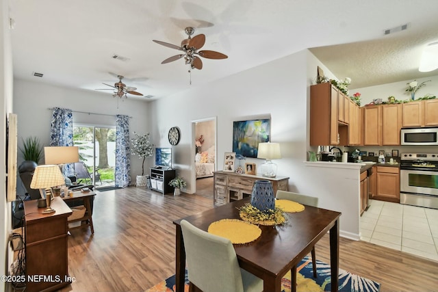 dining space featuring visible vents, light wood-type flooring, and ceiling fan