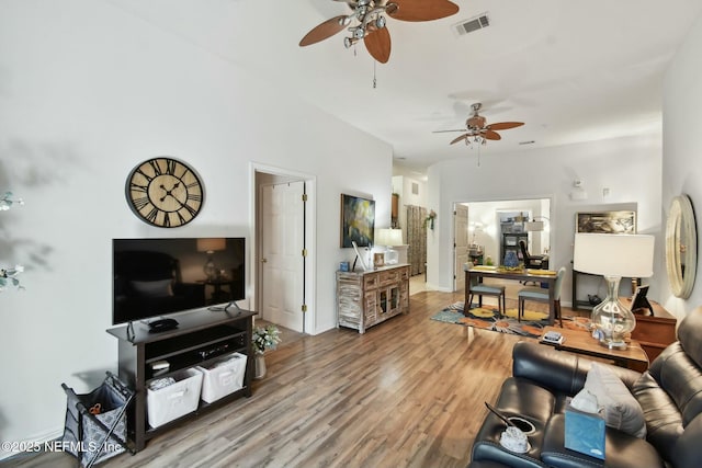 living room with visible vents, wood finished floors, baseboards, and ceiling fan