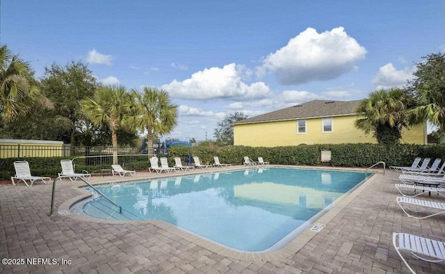 community pool with a patio area and fence