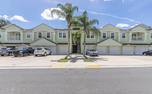 multi unit property featuring an attached garage, driveway, and stucco siding