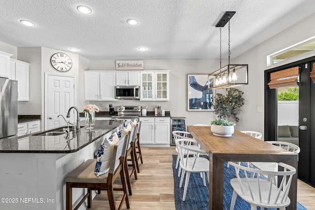 kitchen with wine cooler, white cabinets, appliances with stainless steel finishes, and a sink