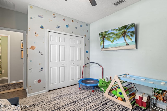 recreation room with visible vents, a textured ceiling, wood finished floors, baseboards, and ceiling fan