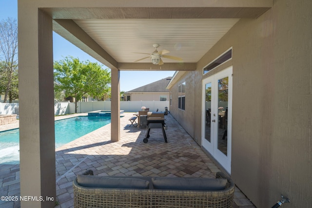 view of pool with a pool with connected hot tub, ceiling fan, french doors, a fenced backyard, and a patio area