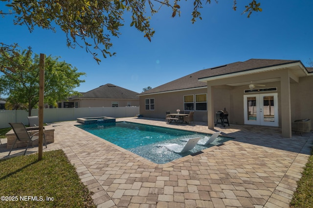 view of swimming pool featuring a pool with connected hot tub, a fenced backyard, french doors, ceiling fan, and a patio area