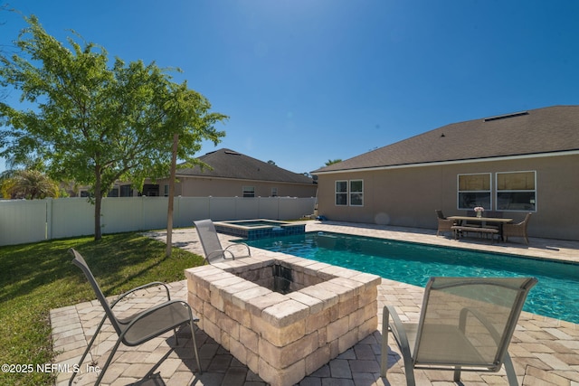 view of swimming pool featuring a pool with connected hot tub, a yard, a patio area, and a fenced backyard