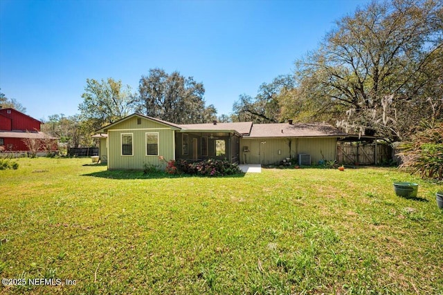 rear view of property with a yard, central AC unit, and fence