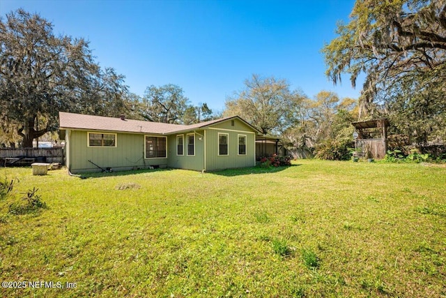 rear view of house featuring a yard and fence