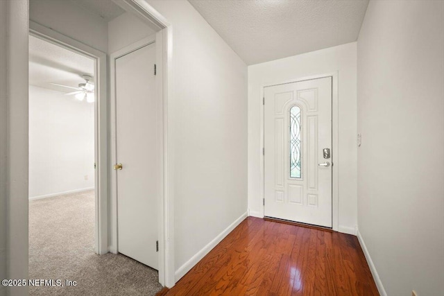 foyer with ceiling fan, wood finished floors, baseboards, and a textured ceiling