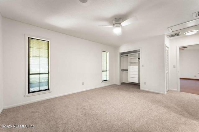 unfurnished bedroom featuring light carpet, visible vents, a ceiling fan, and baseboards