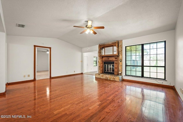 unfurnished living room with visible vents, ceiling fan, vaulted ceiling, wood finished floors, and a textured ceiling